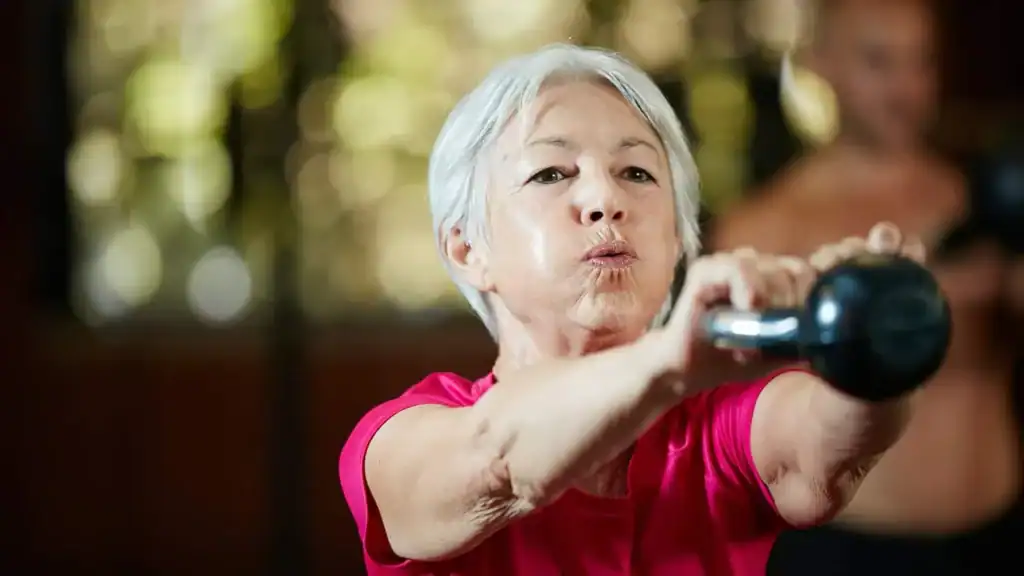 Older woman doing weight training Paisley to help her strength and longevity 