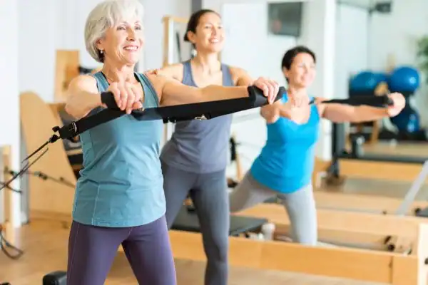 Toning Arms After 60: Empowering Womens Fitness Through Effective Weight Training 2 older woman doing weight training Paisley and resistance in the gym to tone upper arms