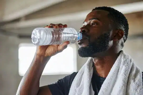 Hydration: The Secret Ingredient for a Toned Stomach and Enhanced Fitness 1 Image of man drinking water to improve hydration Paisley after work out.